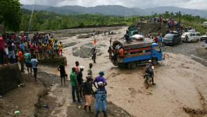 Haitians watch as people cross a river on National Route 2. Hurricane Matthew washed out a bridge at this spot cuttting off much of the southwest of the country from the capital Port au Prince.